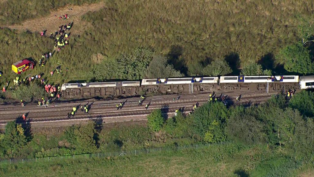 An aerial image of a train on its side.