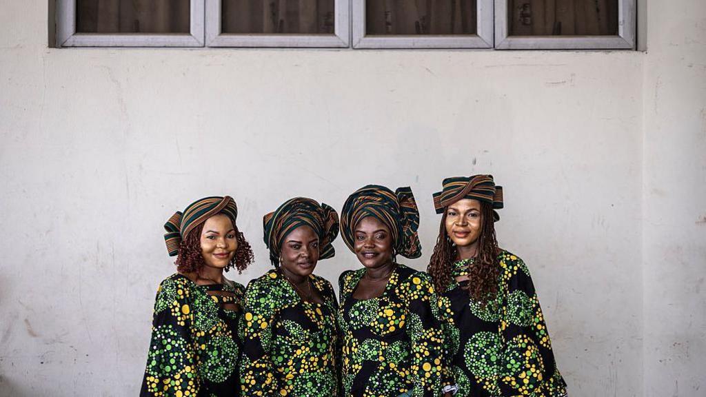  Twin sisters Taiwo and Kehinde Oketikun pose for a photograph with twin sisters Taiwo and Kehinde Adisa. All four wear matching multi-coloured outfits.