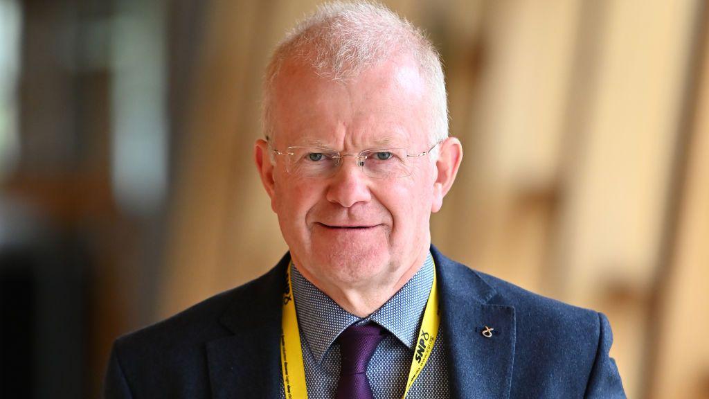 John Mason staring straight at the camera as he makes his way to the debating chamber at Holyrood