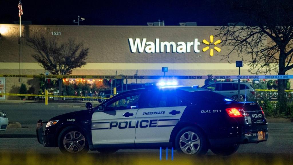 Exterior view of a Walmart supermarket at night, with a police car with flashing blue lights in the foreground