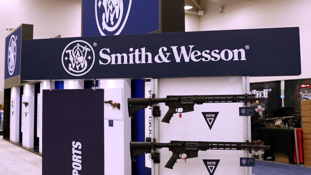 A sign reading 'Smith & Wesson' with large assault rifles below