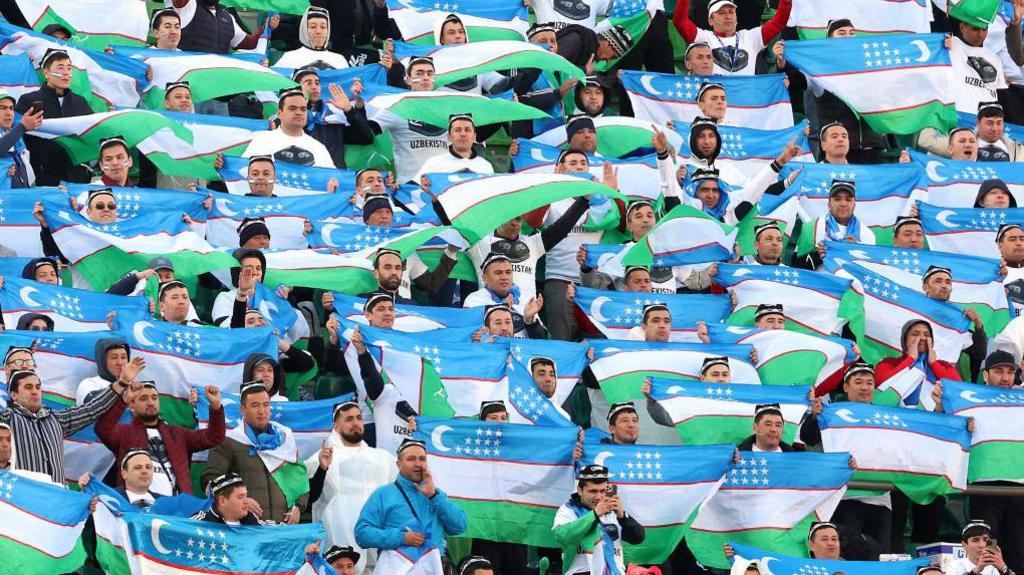 Uzbekistan's fans hold aloft the national flag during a match