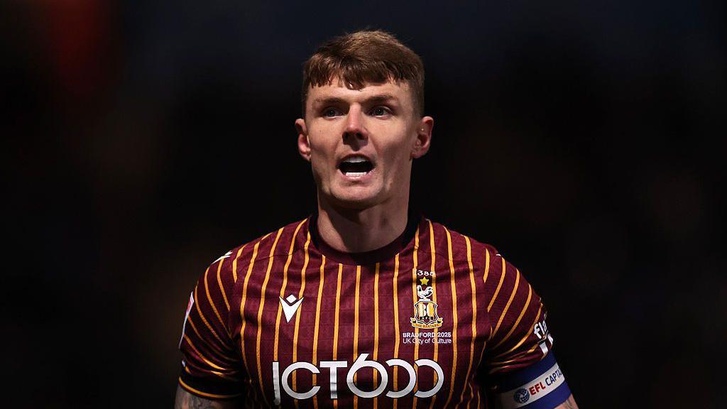 Bradford City captain Max Power shouting looking forward in night game, wearing club's home colours