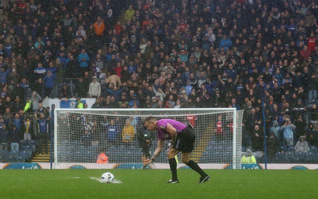 A referee rolls a ball that splashes on the pitch at Blackburn Rovers