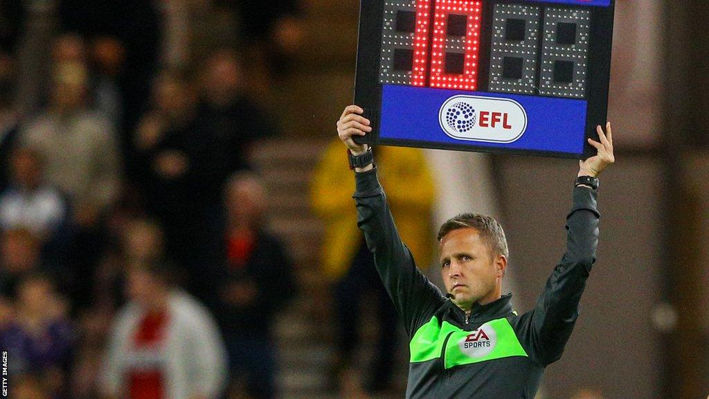 An EFL match official holds up a board indicating 10 minutes of added time