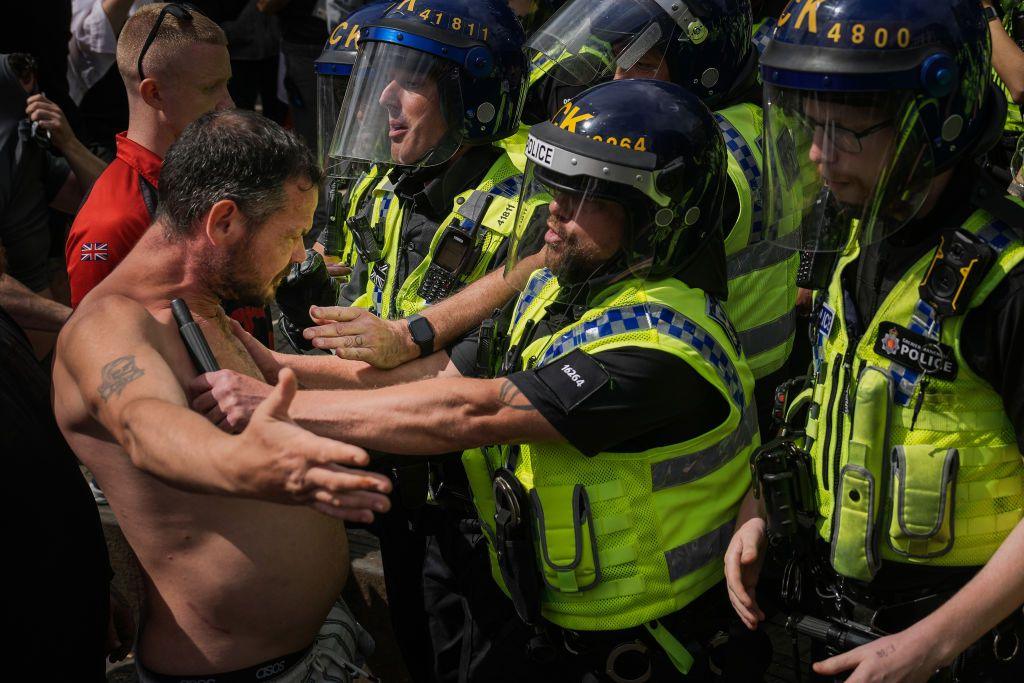 Riot police pushing a protester back