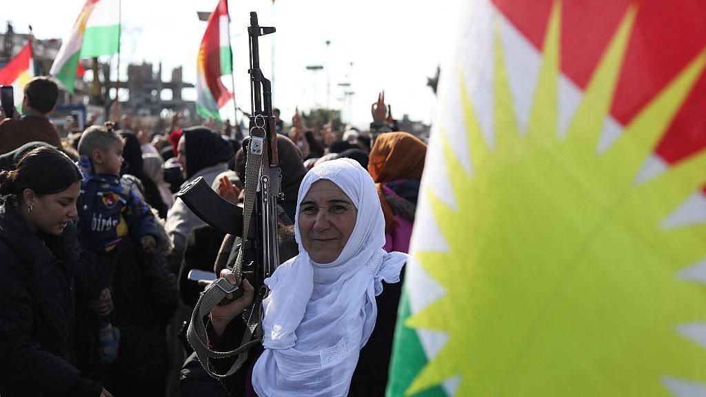 Një grua mban një pushkë në një protestë të kurdëve kundër një ofensive qeveritare në Sirinë verilindore, në Qamishli, Siri (20 janar 2026)