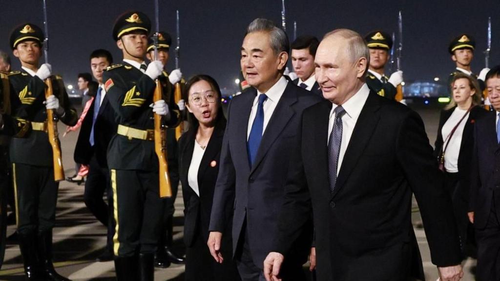 Russian President Vladimir Putin (C-R) is escorted by China's Foreign Minister Wang Yi (C-L) upon his arrival in Beijing, China