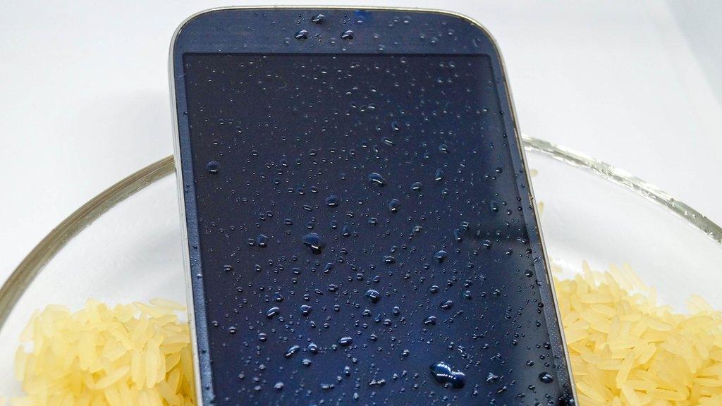 A wet unbranded phone in a bowl of dry rice - stock image