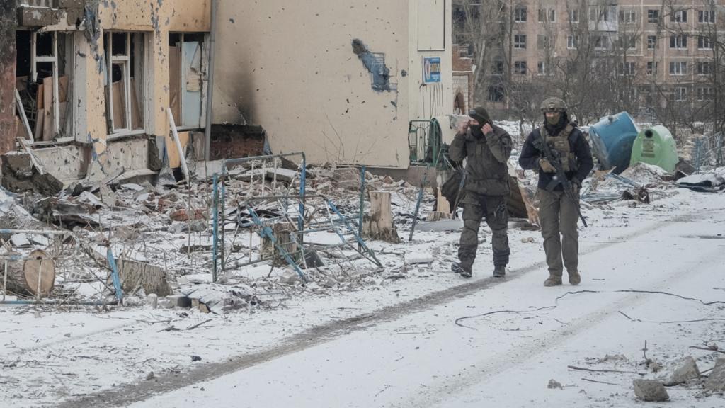 Ukrainian servicemen walk an empty street near buildings damaged by a Russian military strike, in the front line city of Vuhledar