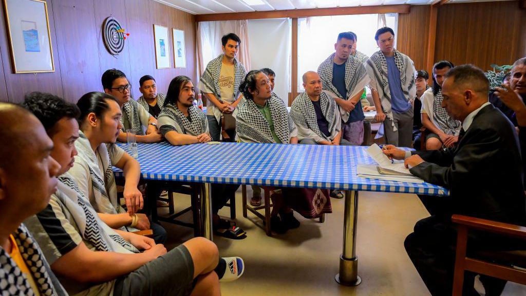 Captive crew members of the Galaxy Leader cargo ship meet the honorary consul of the Philippines, Muhammad al-Jamal (R), at venue in the port city of Hudaydah on 4 October 2024