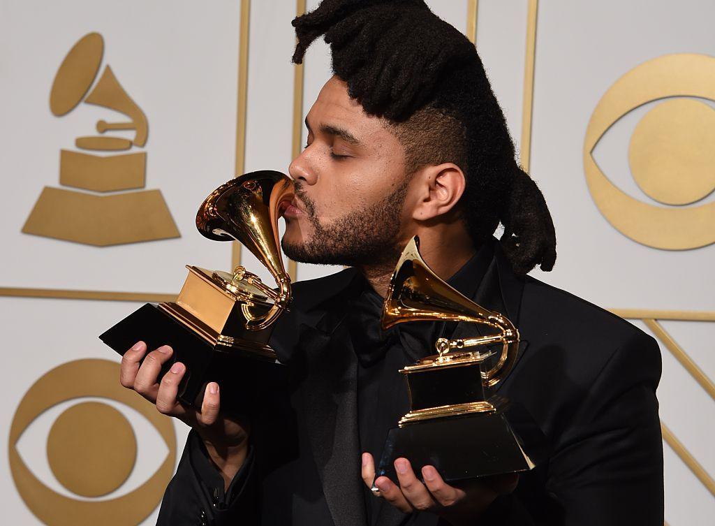 The Weeknd kisses one of two Grammy trophies