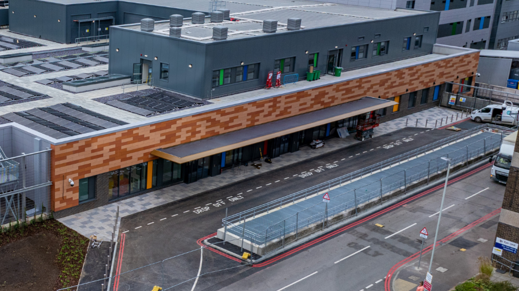 Aerial shot of the outside of Queen Alexandra's emergency department. It has a brown facade with drop-off bays outside.