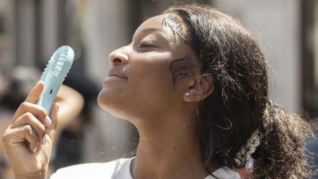 Woman cooling herself with fan