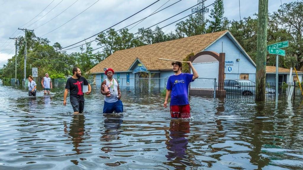 Residents walk through a flooded street in North Tampa