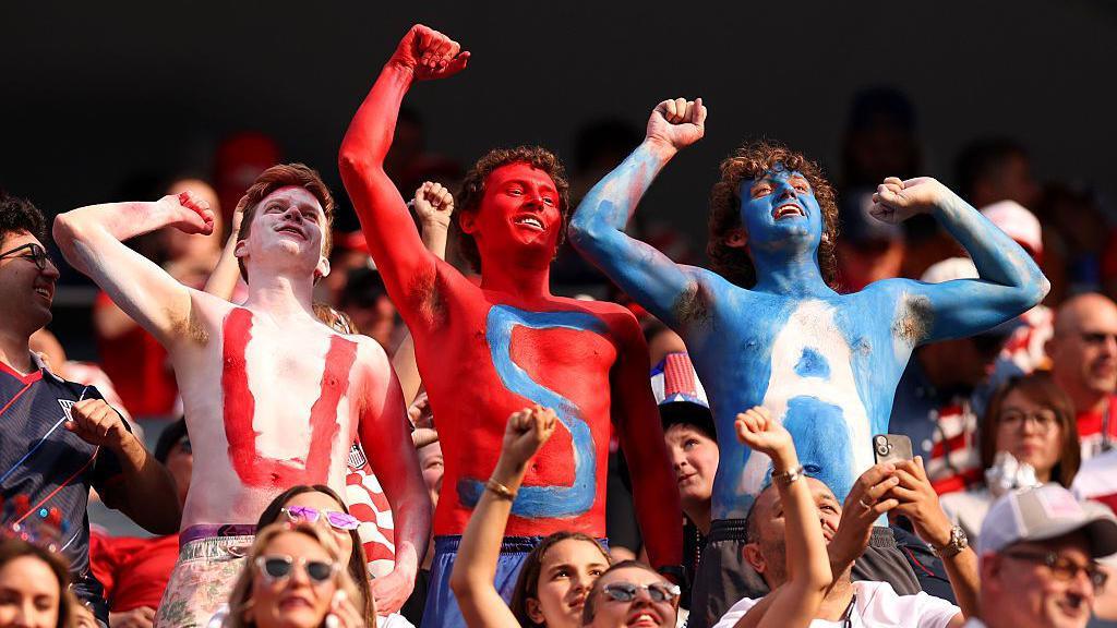 Three men paint their upper bodies in white, red and blue body paint that reads USA as they cheer from the stands at Los Angeles stadium before the FIFA World Cup 2026 Group D match between Türkiye and USA on 25 June 2026 
