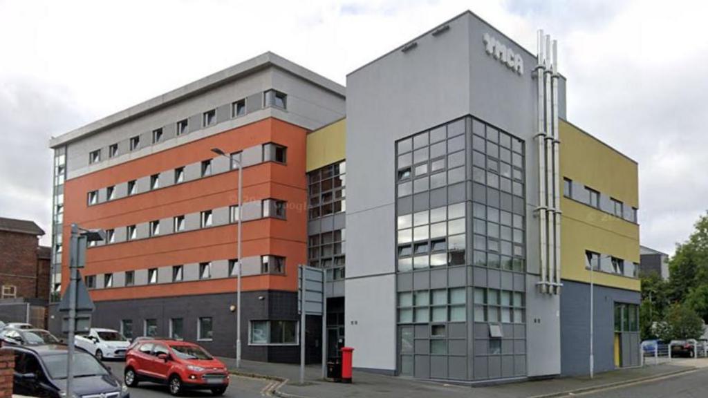 Modern four storey tower block building with orange, grey and yellow external walls