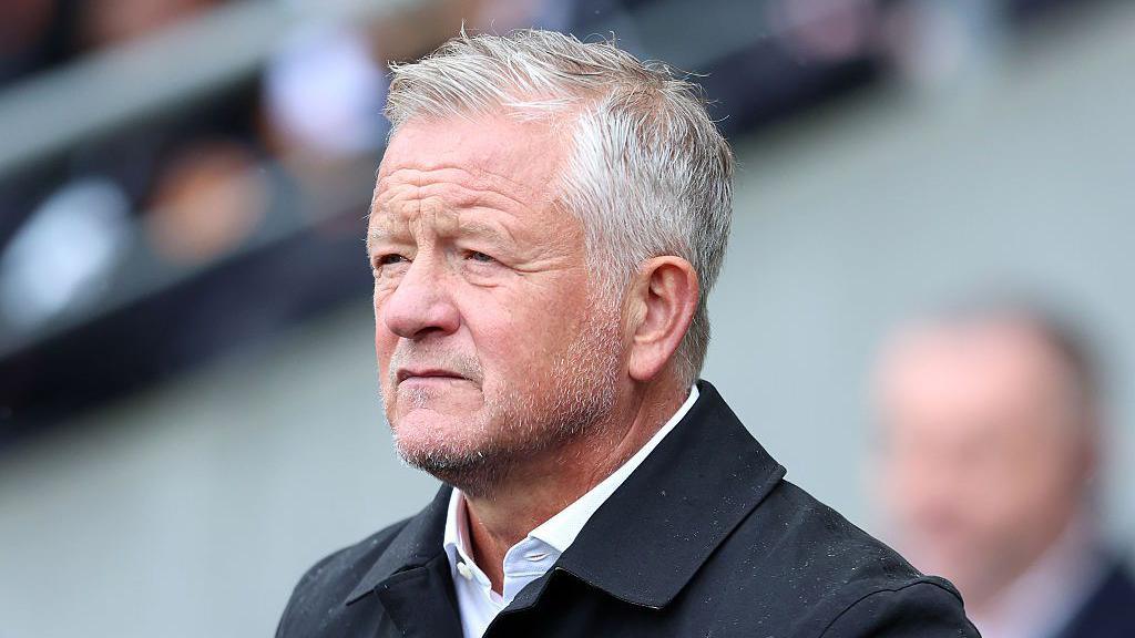Unshaven Sheffield United manager Chris Wilder looking forward in open neck shirt and rain jacket