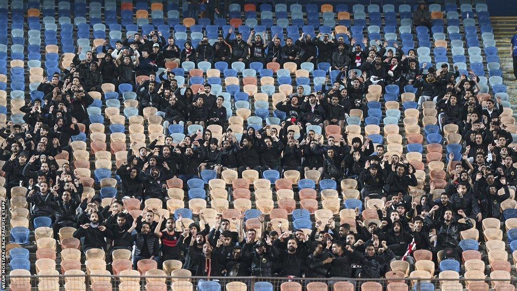 Zamalek fans in black form an angry face emoji in the stand