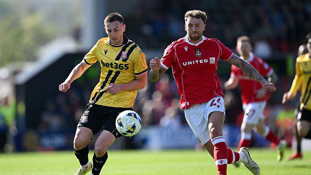 Robert Bozeník of Stoke City is tackled by Dan Scarr of Wrexham during a match between Wrexham AFC and Stoke City at Stok Cae Ras