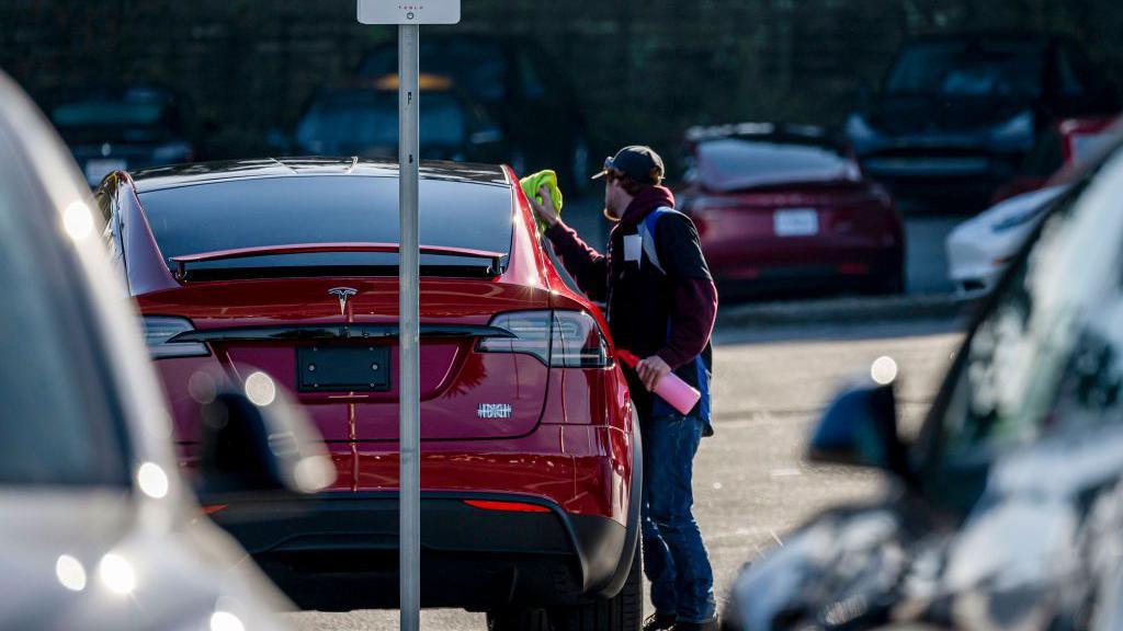 A worker cleans a Tesla Model X at the company's store in Colma, California, US, on Thursday, Jan. 2, 2025. 