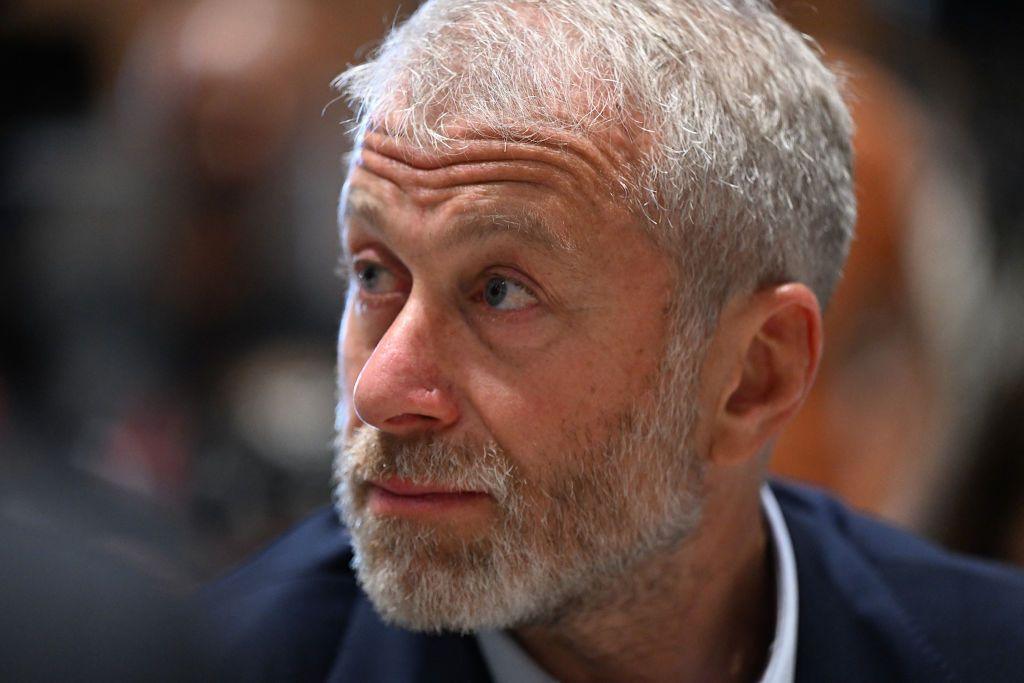 A close of up a bearded Roman Abramovich in a blue suit and white shirt looking to his right