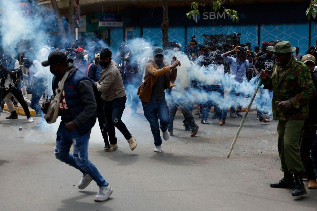 Plain clothes Kenyan police officers run for cover after the teargas they lobbed to protesters was returned to them, during a demonstration on 18 June.