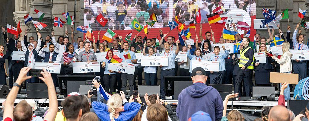 Competing teams holding signs and flying their flags at the World Tram Driver Championship.