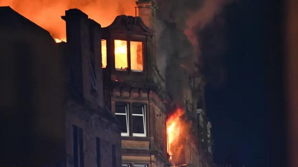 Fire rips through the upper floors of a tenement block at night