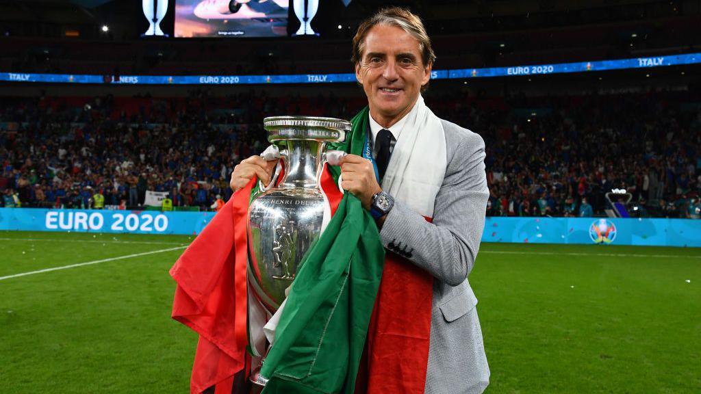 Roberto Mancini holds the EURO 2020 trophy on the pitch at Wembley Stadium after Italy's penalty shootout victory over England
