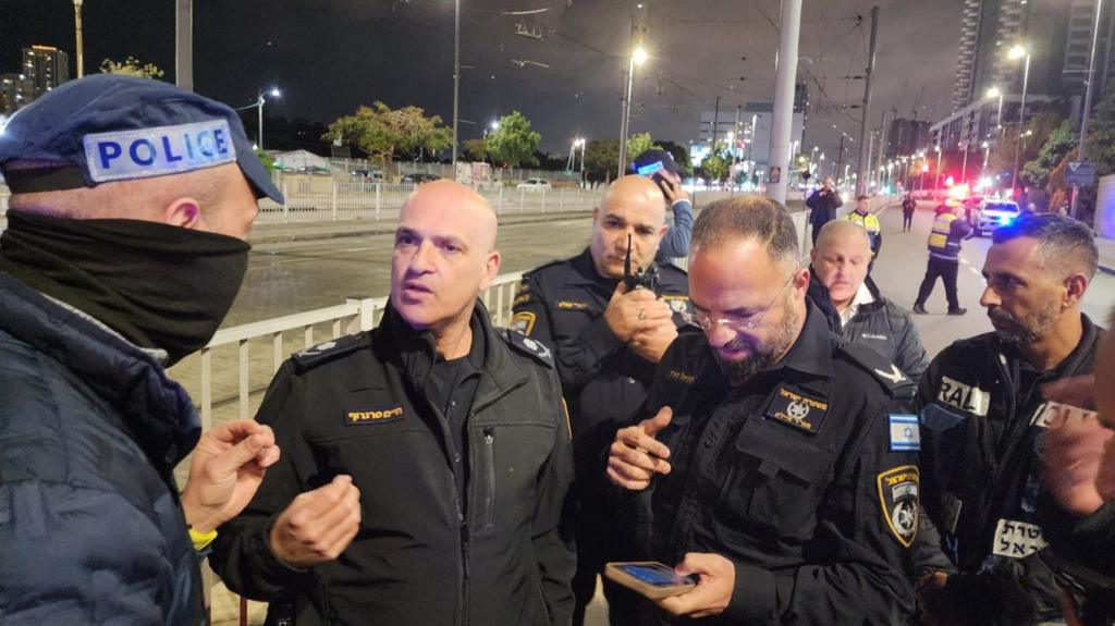 Six members of Israeli police gather around each other on the street.