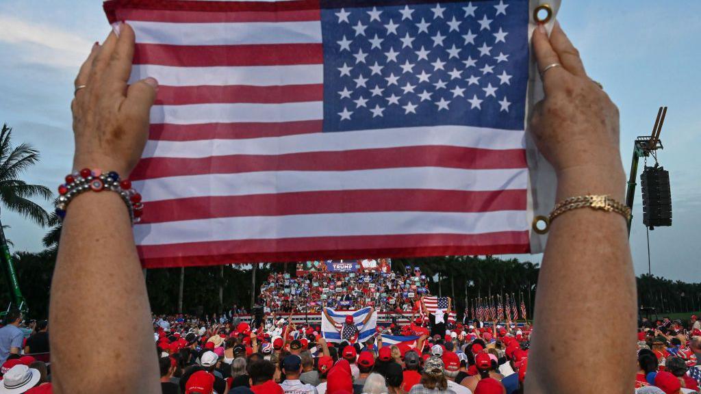 A US flag being held up at a political rally