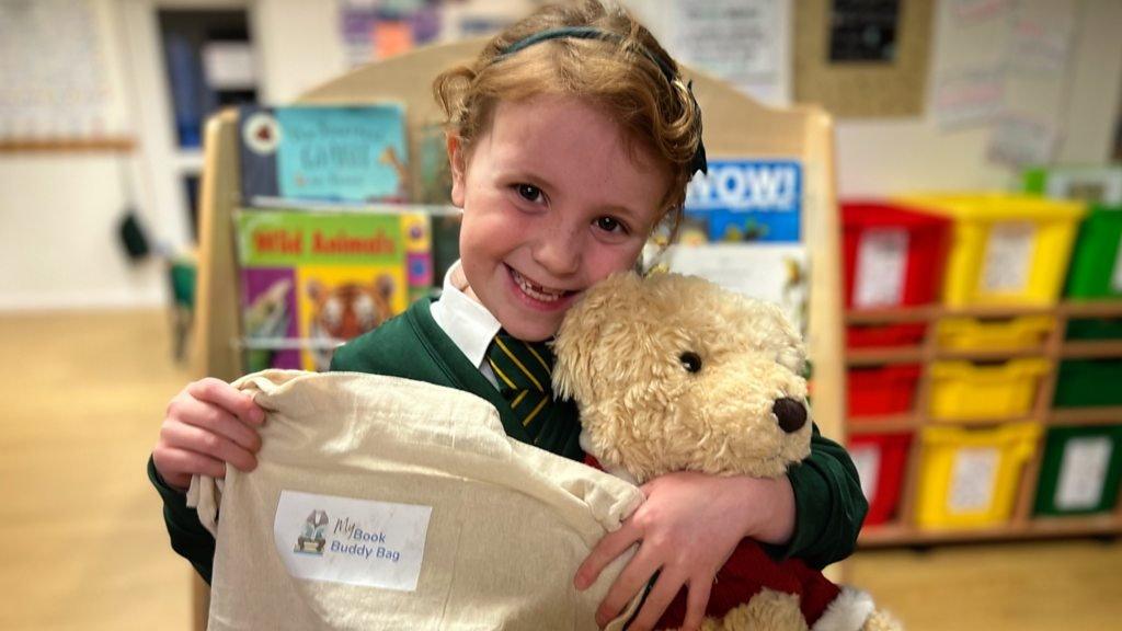 7-year-old Annie holds a book buddy bag and her book buddy Hagrid