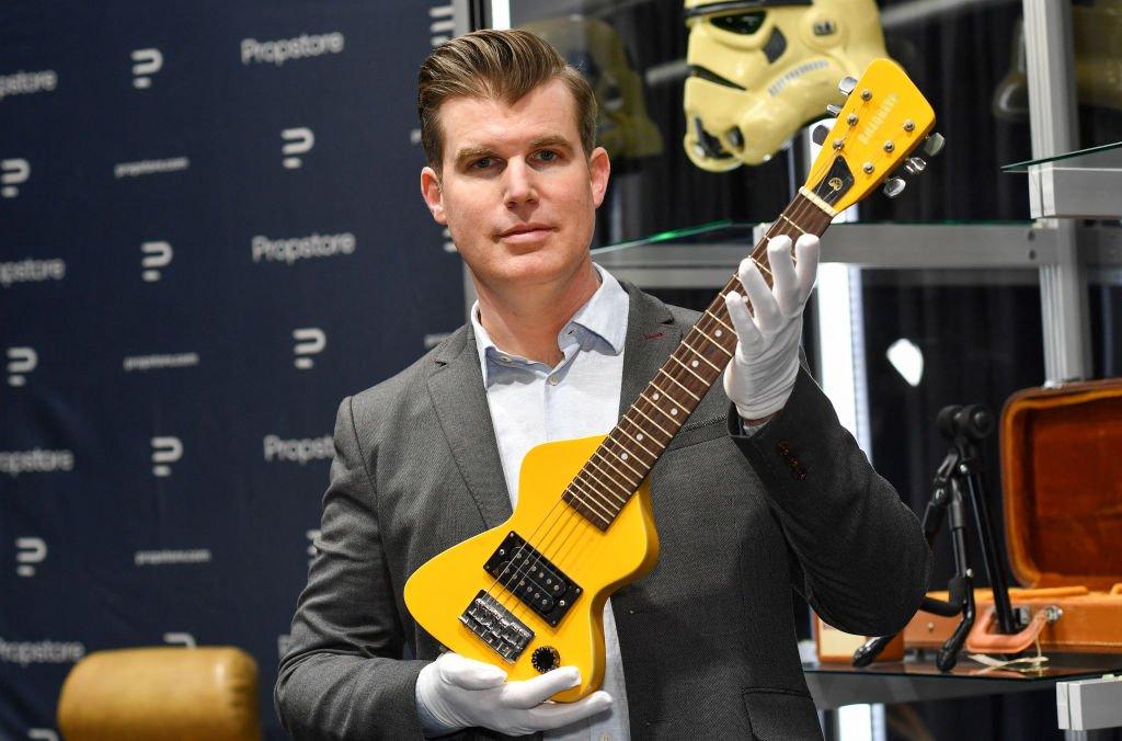Brandon Alinger, Chief Operating Officer at Propstore, holds Marty McFly's guitar from the film Back to the Future.