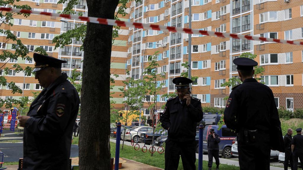 Russian law enforcement officers stand guard near a damaged multi-storey apartment block following a reported drone attack in Moscow, Russia, May 30