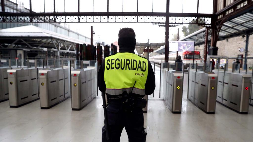 A private security agent stands guard at an empty station in Madrid