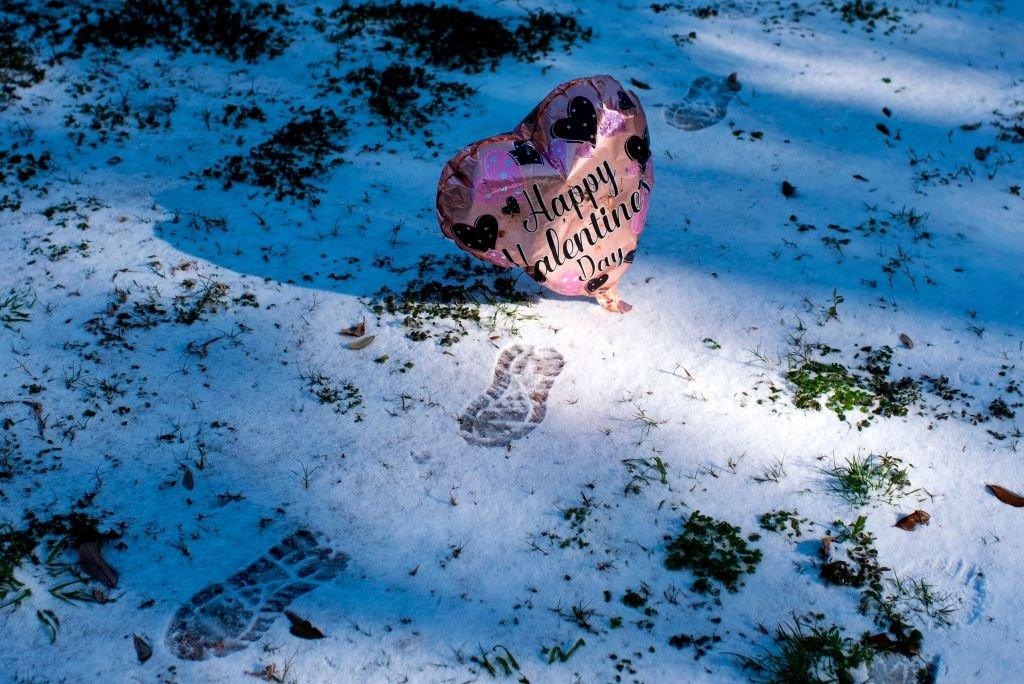 A Valentine's Day balloon floats past footprints in the snow in Houston