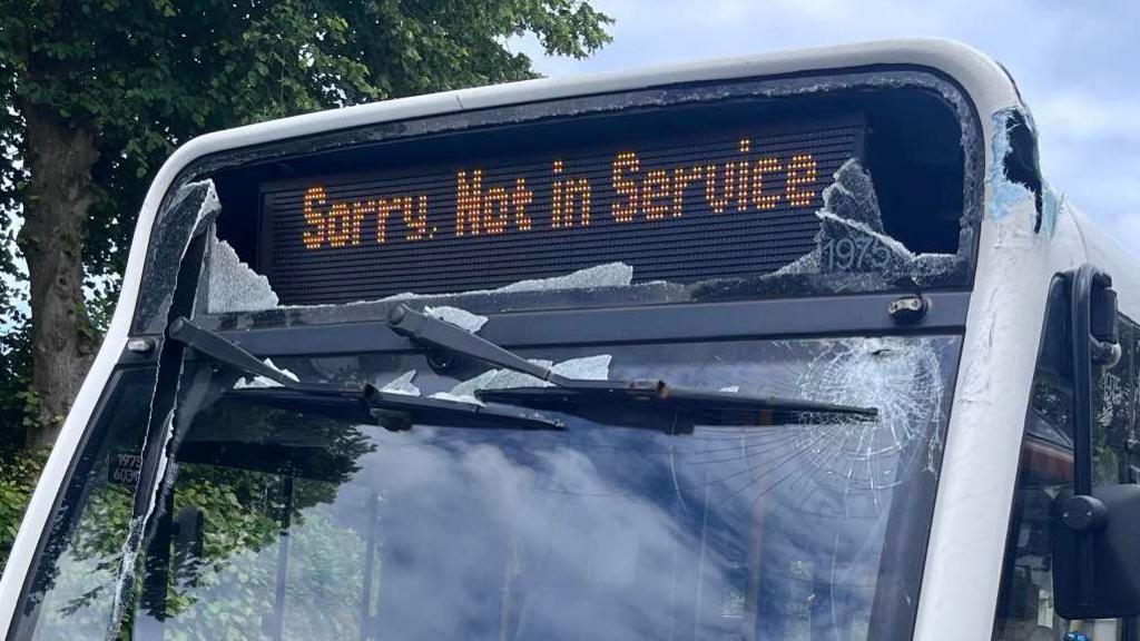 A bus with a smashed windscreen, electronic sign, and chassis. Electronic sign says: Sorry, Not in Service.