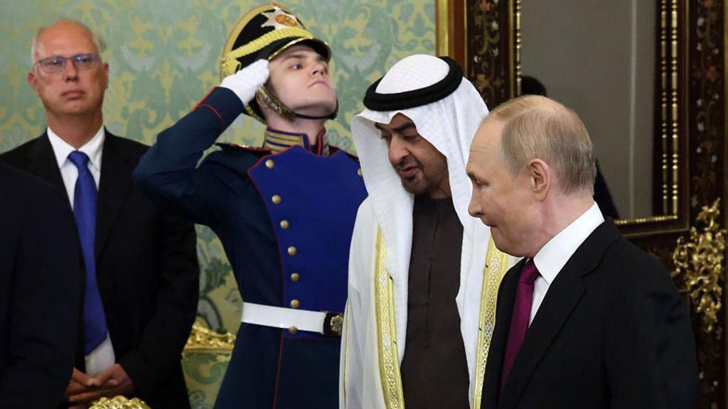 Russian President Vladimir Putin (R) and UAE President Sheikh Mohamed Bin Zayed Al Nahyan (C) enter a room as a soldier salutes and Dmitriev looks on