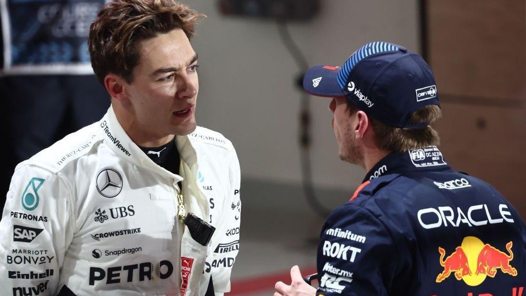 George Russell and Max Verstappen talk to each other in the pit lane at the Qatar Grand Prix