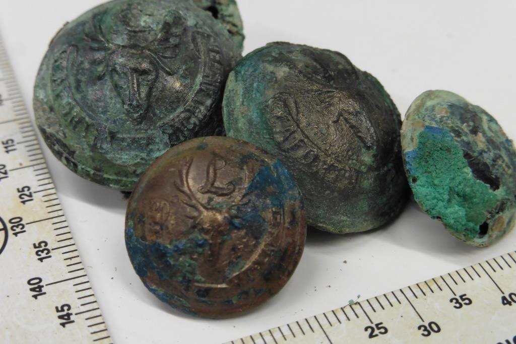 Army uniform buttons recovered from a WW1 hospital, turned green with age, and a tape measure to show the size