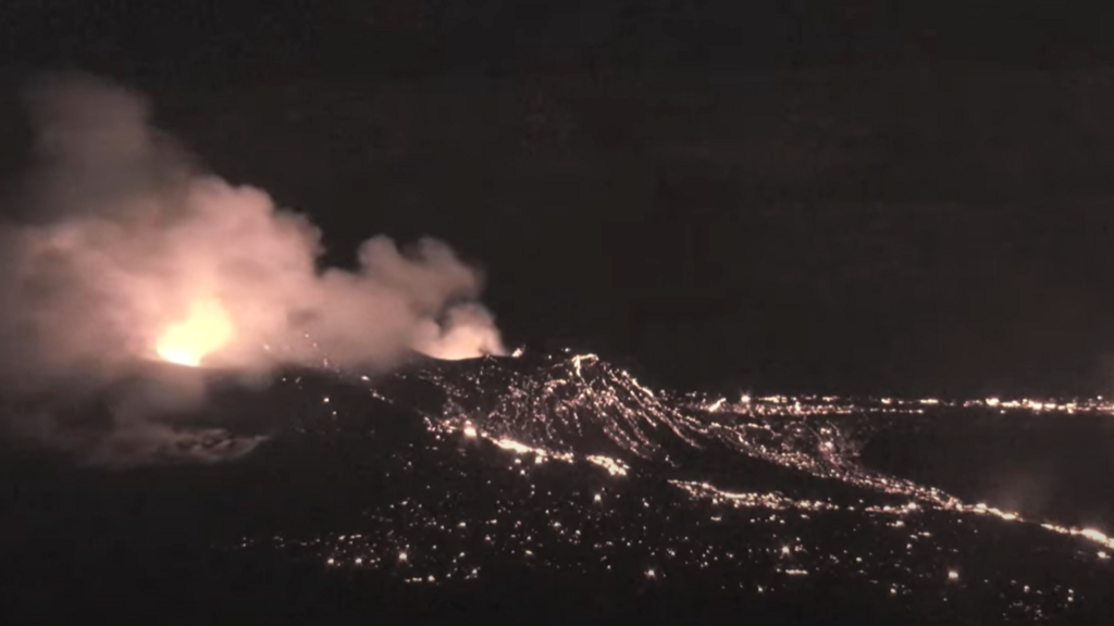 Night shot of Kilauea volcano erupting, clouds of smoke coming out from the top of the crater
