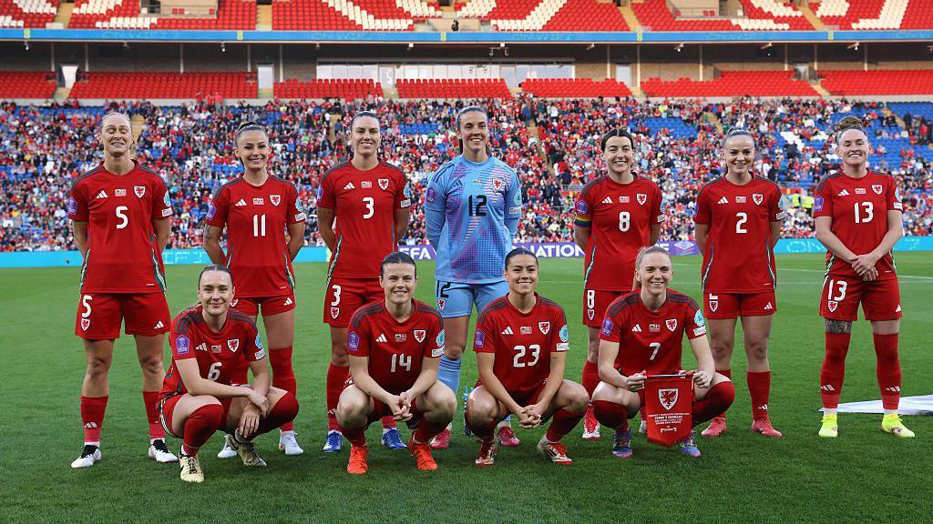 The Wales women's football team line up for their team photograph at a stadium