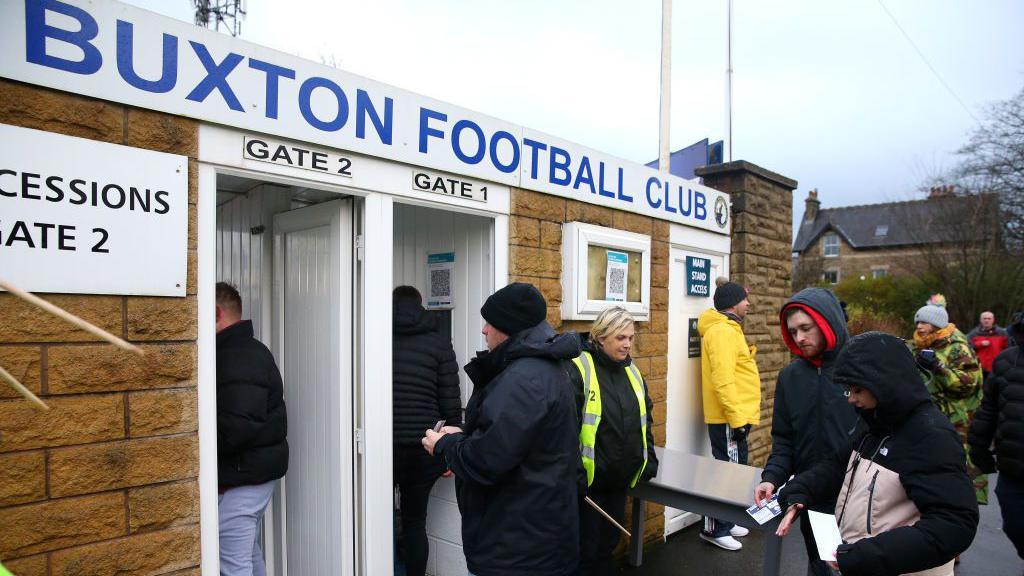 An image of fans entering Buxton FC's stadium ahead of an FA Cup tie against Morecambe