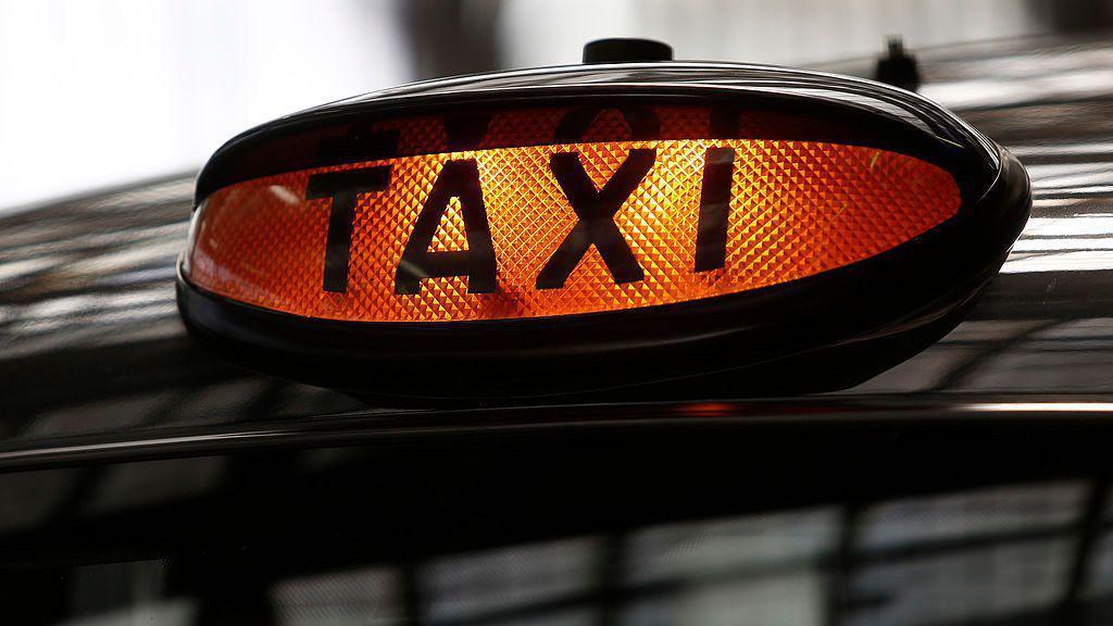 An orange taxi light on top of a black cab.