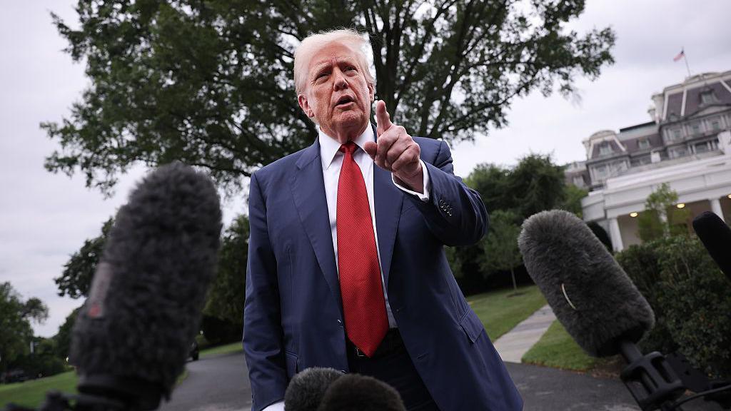 President Trump pointing at a reporter whilst surrounded by microphones outside the White House