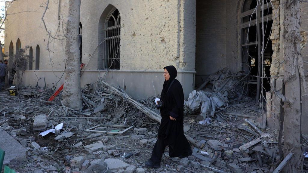 A woman walks through debris of a damaged building at the Sharif University in Tehran, Iran