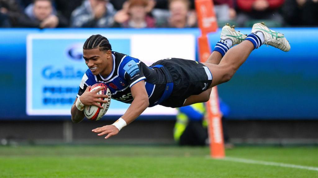 Tyler Offiah jumps over the line to score a try for Bath