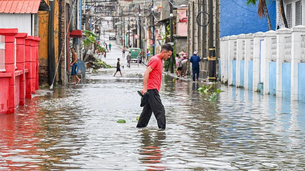 A man walks through a flooded street in a neighbourhood affected by Hurricane Melissa in Santiago de Cuba.