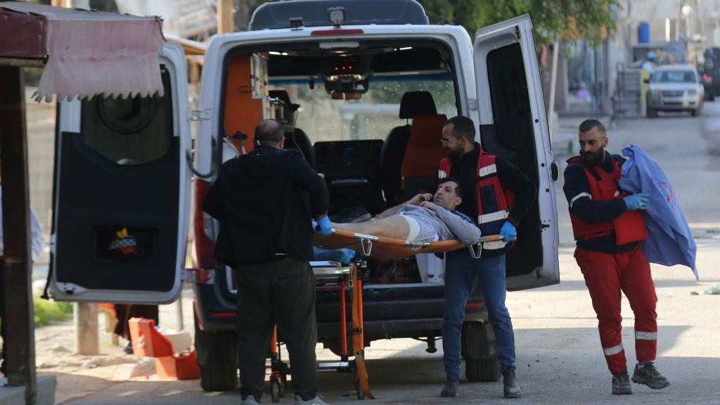 Paramedics evacuate a Palestinian man wounded during a major operation by Israeli security forces in Jenin, in the occupied West Bank (21 January 2024)